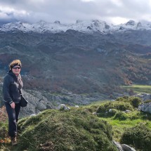 Marion on the summit of 1279 meters high Porra de Enol  in the western Picos de Europa with snowy mountains in the south